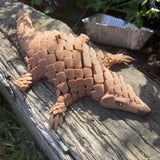 3D printed articulated Pangolin. Shown in the sun on a log in the garden. 