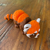 Orange Brown and White 3D printed Red Panda. Designed by Matmires and printed by Pilola. Shown on a wooden background