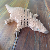 3D Printed Brown Pangolin. Shown lying down on a wooden background
