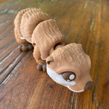 3D Printed Articulated Otter. Designed by Matmires and printed by Pilola. Showing close up of head anf body on a wooden background