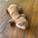 3D printed Otter. Designed by Matmires and printed by Pilola. Shown lying down on a wooden background