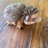 3D printed cute brown hedgehog. Showing the side view on a wooden background