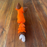 3D printed fox shown on a wooden background, back view, facing away with bushy tail in view
