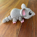 3D printed cute grey mouse. Designed by Matmires and printed by Pilola. Showing side view on a wooden background